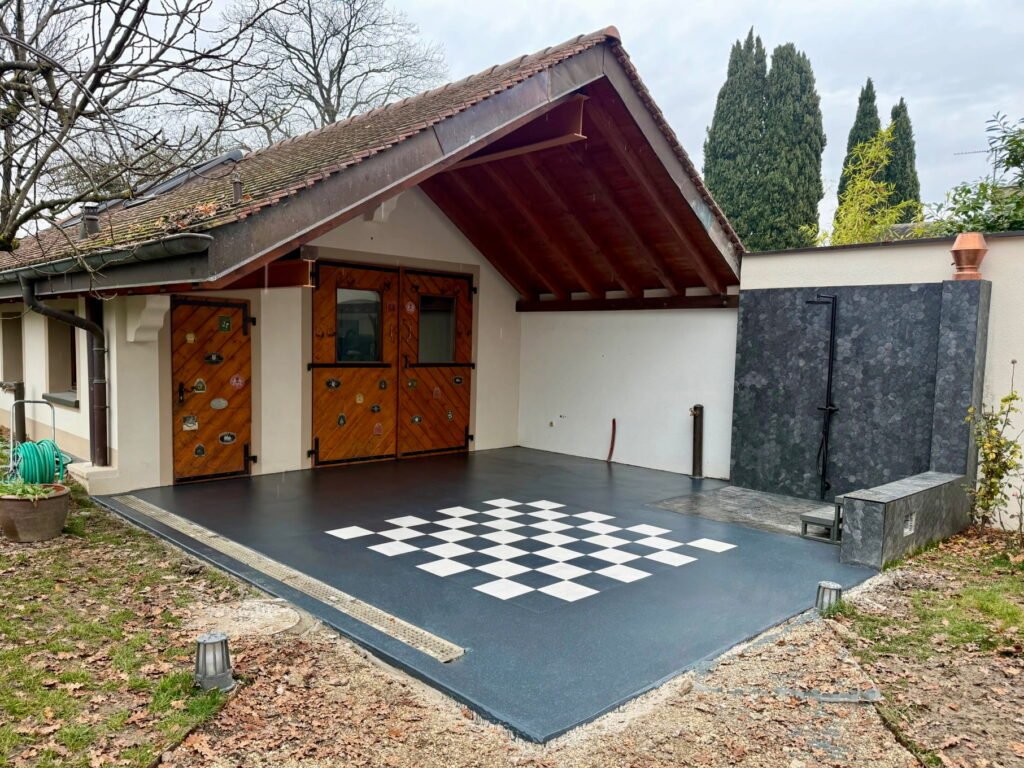 Terrasse extérieure avec revêtement décoratif en résine PMMA antidérapante et motif échiquier réalisée par Saphir Résine